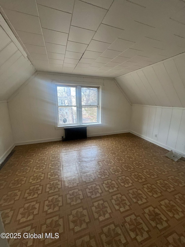 bonus room featuring lofted ceiling, radiator, and baseboards