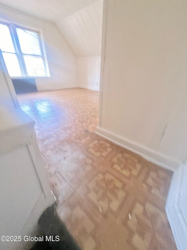 additional living space featuring baseboards and vaulted ceiling