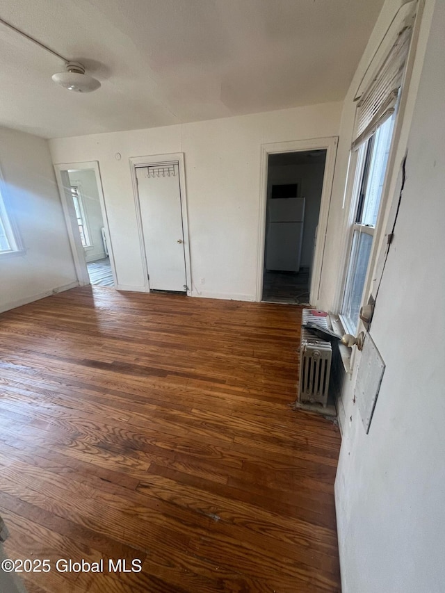 interior space with ensuite bath, freestanding refrigerator, and dark wood-type flooring