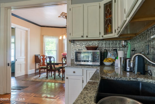 14 Pleasant St, Ballston Spa, NY 12020 - kitchen featuring stainless steel microwave, a sink, decorative backsplash, ornamental molding, and wood finished floors