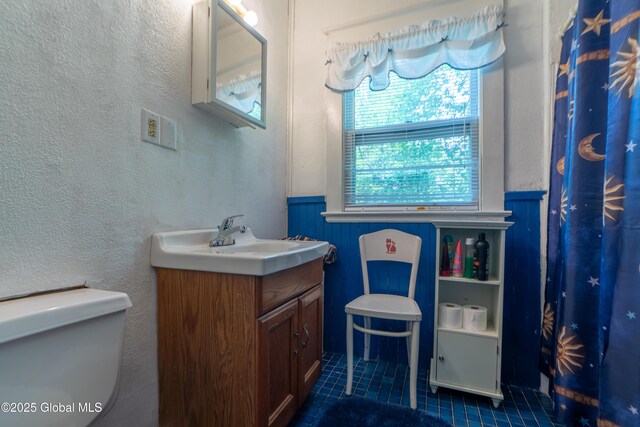 14 Pleasant St, Ballston Spa, NY 12020 - full bath with tile patterned floors, vanity, toilet, and a wainscoted wall