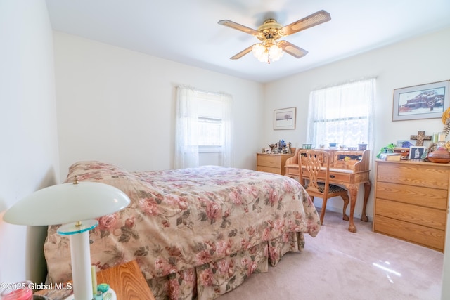 bedroom featuring multiple windows, a ceiling fan, and light colored carpet