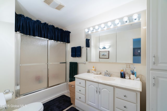 full bath with vanity, visible vents, toilet, and bath / shower combo with glass door