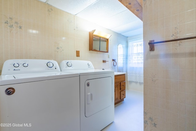laundry room with washing machine and dryer, laundry area, and tile walls