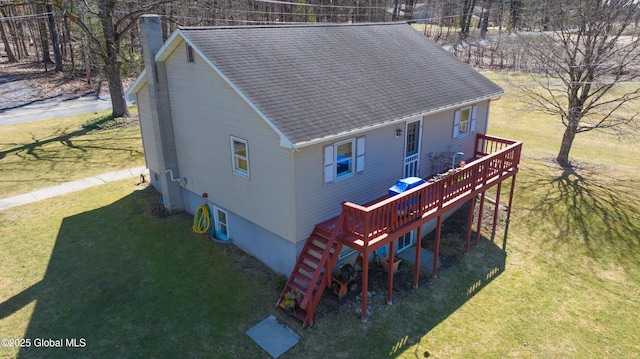 exterior space featuring a shingled roof, a deck, and a yard