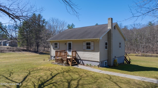 view of front facade with a chimney, a shingled roof, and a front yard