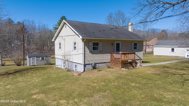 rear view of property with an outbuilding, a lawn, a storage shed, a shingled roof, and a chimney
