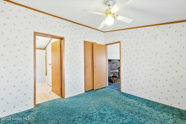 unfurnished bedroom with carpet floors, a ceiling fan, wallpapered walls, and crown molding