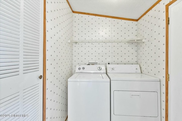 laundry area with washing machine and clothes dryer, ornamental molding, wallpapered walls, and laundry area