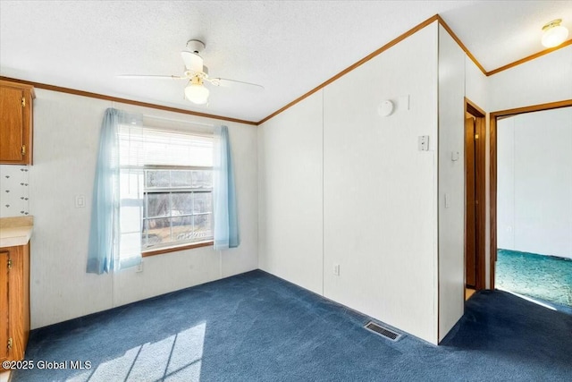 interior space with a textured ceiling, visible vents, ornamental molding, ceiling fan, and dark carpet