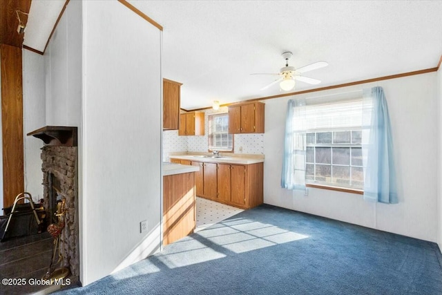 kitchen with light countertops, a sink, ceiling fan, light carpet, and brown cabinets
