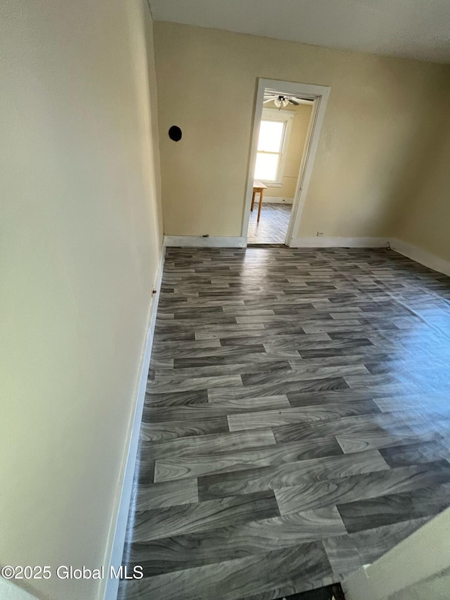 unfurnished room with baseboards and dark wood-type flooring
