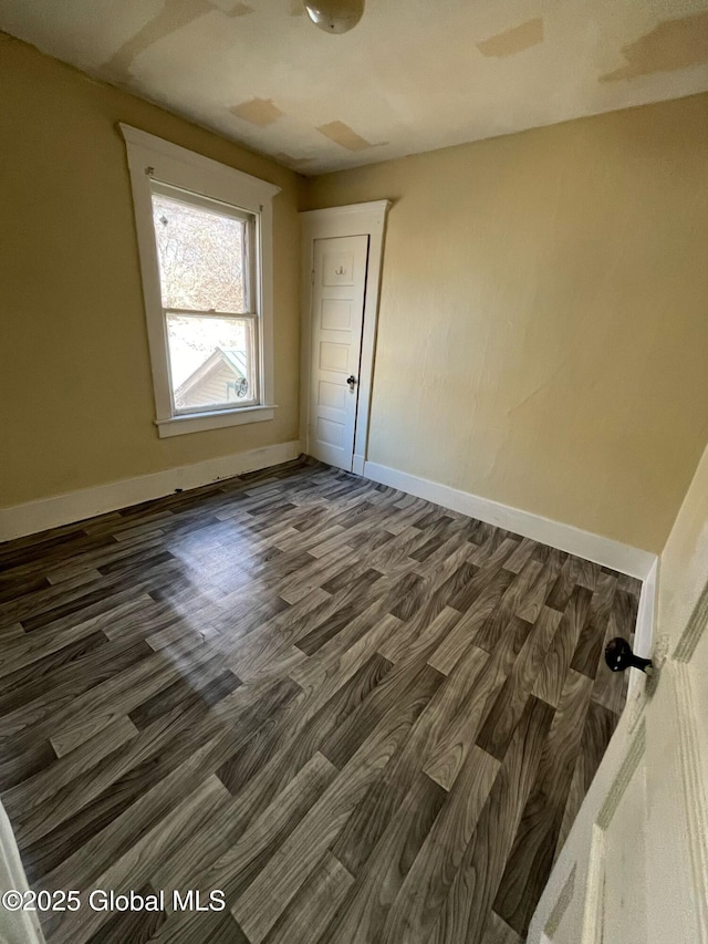 unfurnished room with dark wood-style floors and baseboards