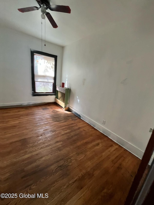 unfurnished room featuring dark wood finished floors, baseboards, and a ceiling fan