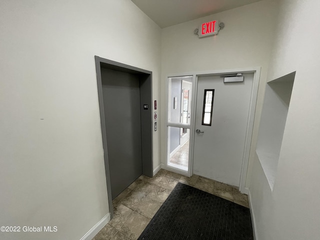 hallway with elevator and baseboards