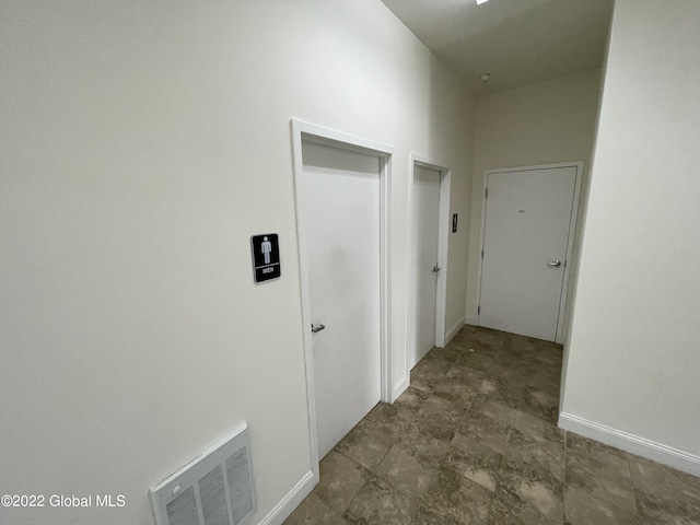 hallway featuring baseboards and visible vents