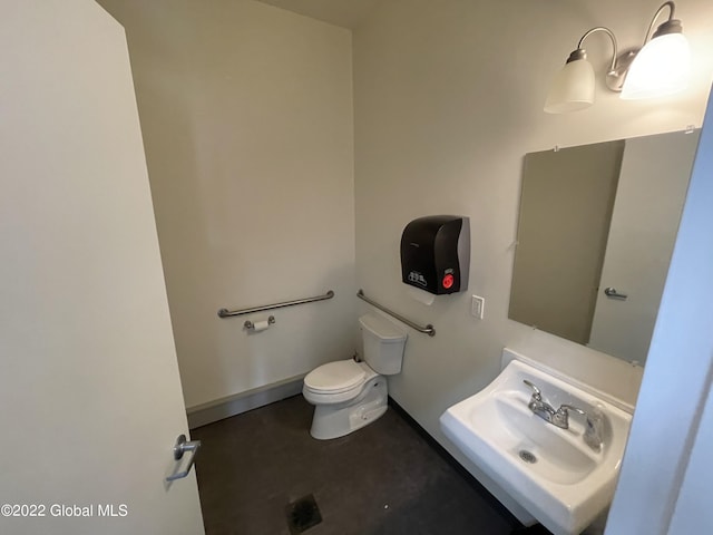 half bath with toilet, a sink, and baseboards