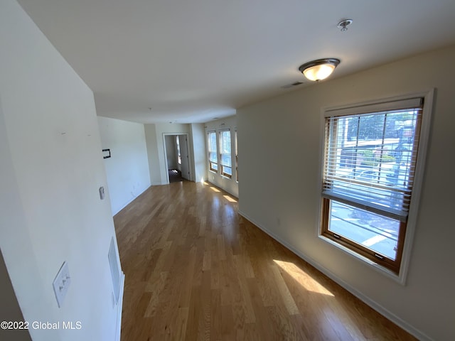 corridor featuring baseboards, visible vents, and wood finished floors
