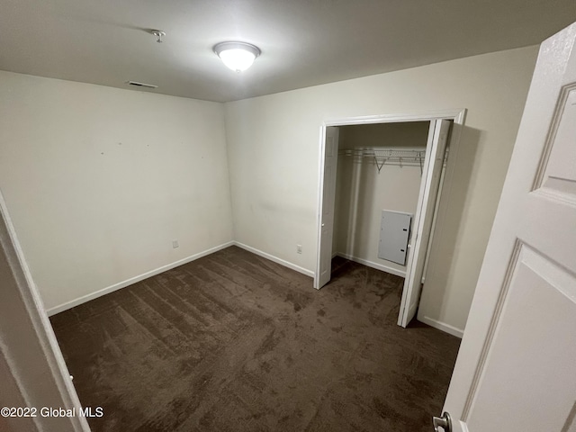unfurnished bedroom with a closet, baseboards, dark carpet, and visible vents