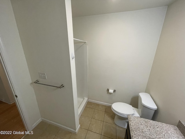 full bath with toilet, baseboards, tile patterned flooring, and walk in shower