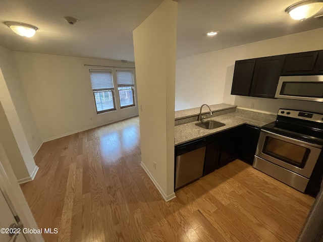 kitchen with a sink, light wood-style flooring, baseboards, and appliances with stainless steel finishes