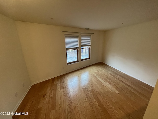 spare room with baseboards and wood finished floors