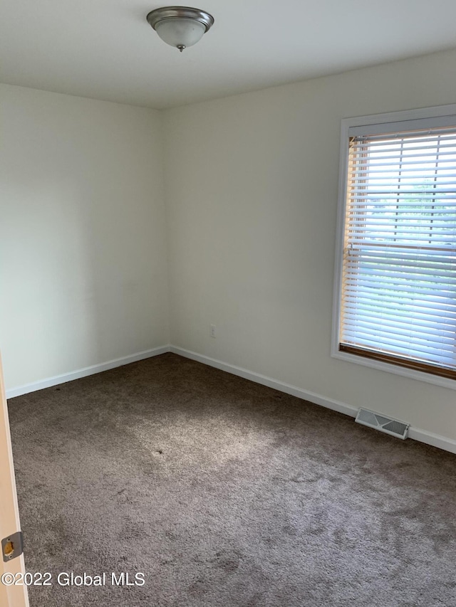 unfurnished room featuring baseboards, carpet floors, visible vents, and a healthy amount of sunlight