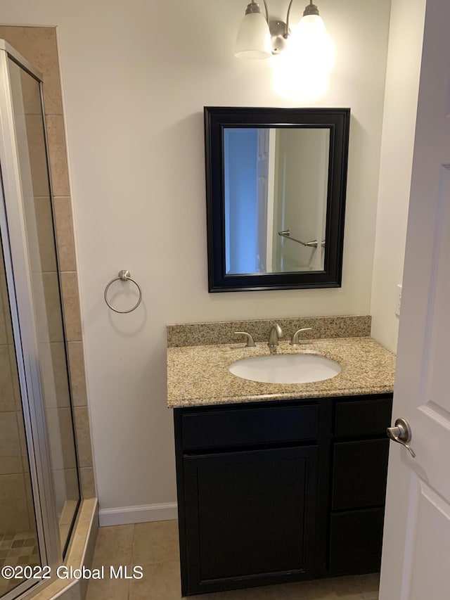 bathroom featuring vanity, baseboards, tile patterned flooring, and a shower stall