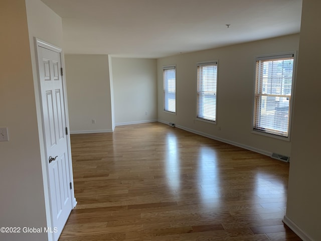 spare room with baseboards, visible vents, wood finished floors, and plenty of natural light