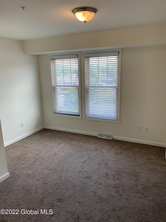 spare room featuring baseboards, carpet floors, and visible vents