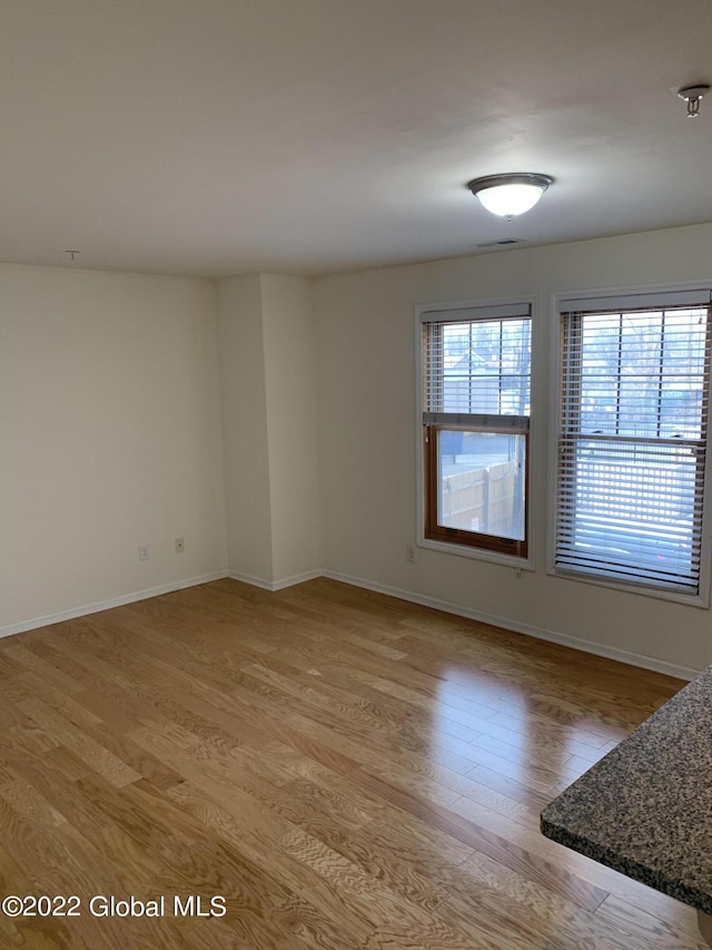 unfurnished room with baseboards, light wood-type flooring, and visible vents