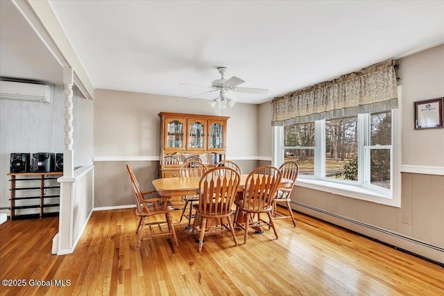 23 Leggett Rd, Ghent, NY 12075 - dining room featuring a ceiling fan, a baseboard radiator, light wood-style flooring, a wall mounted air conditioner, and wainscoting