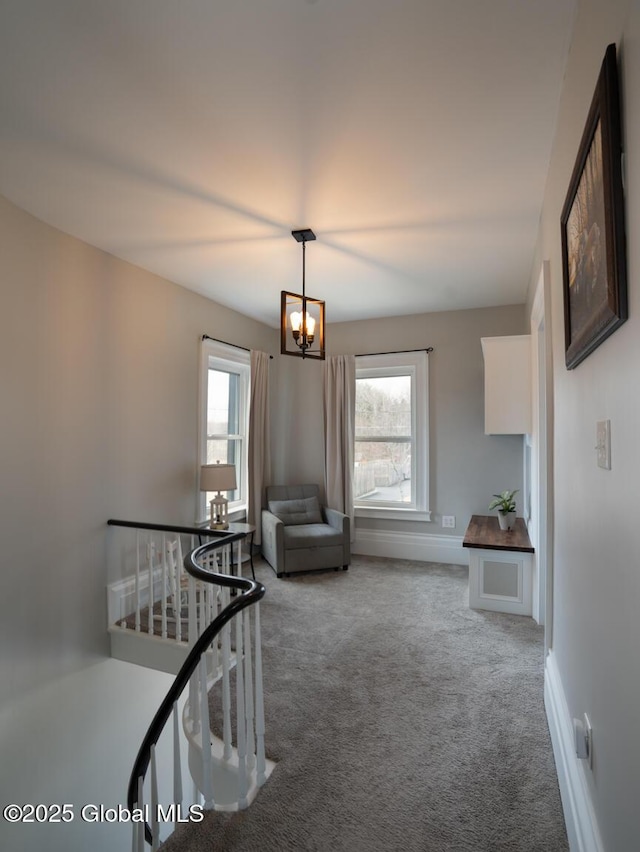 interior space featuring multiple windows, baseboards, carpet flooring, and an inviting chandelier