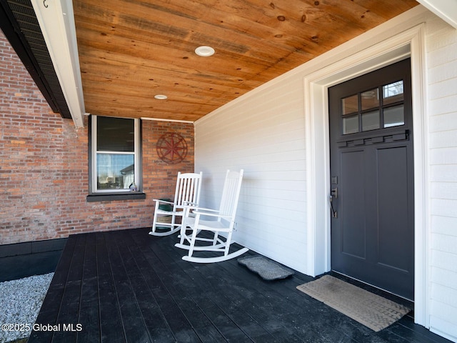 view of exterior entry with a porch and brick siding