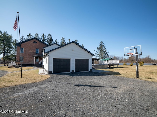 exterior space featuring gravel driveway, a garage, and a lawn