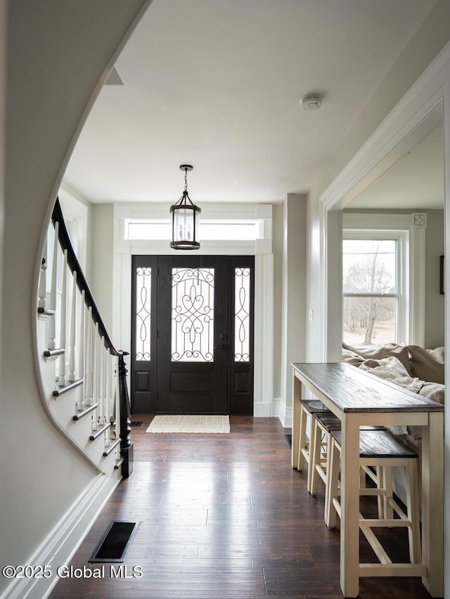 foyer with baseboards, stairs, dark wood-style floors, and visible vents