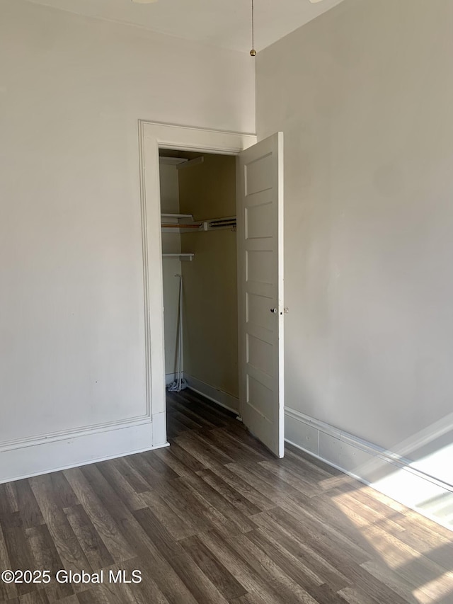 unfurnished bedroom with baseboards, a closet, and dark wood finished floors