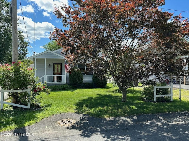 view of property hidden behind natural elements with a front lawn and a porch