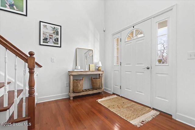 entryway with baseboards, wood finished floors, and stairs