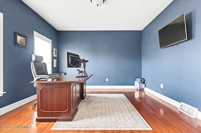 office space with wood finished floors, baseboards, and visible vents