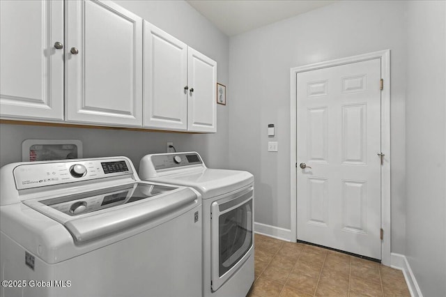 clothes washing area with light tile patterned floors, washer and clothes dryer, baseboards, and cabinet space