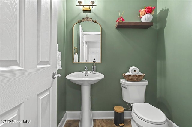 half bath with a sink, toilet, and baseboards