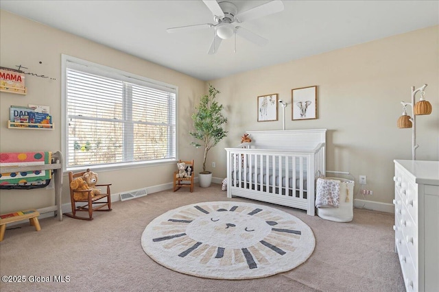 bedroom with a nursery area, baseboards, visible vents, and carpet floors