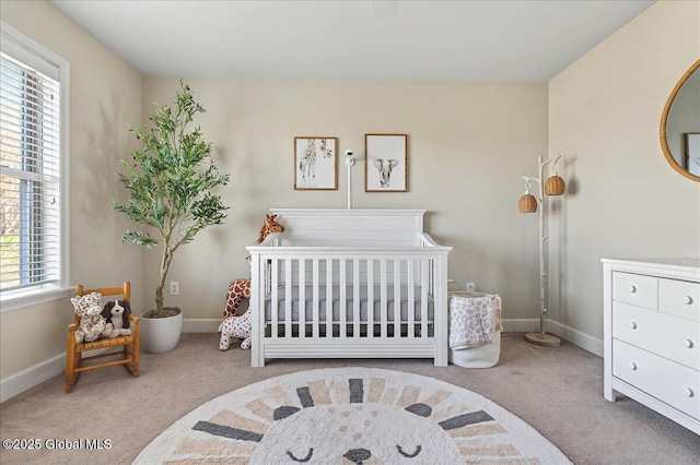 bedroom with carpet flooring, baseboards, multiple windows, and a nursery area