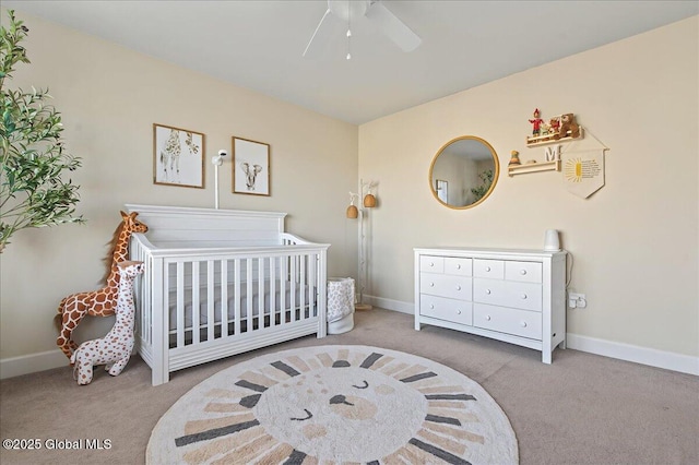 carpeted bedroom with baseboards, a ceiling fan, and a nursery area