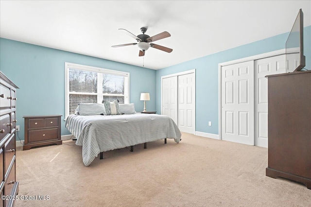 bedroom featuring multiple closets, a ceiling fan, light carpet, and baseboards