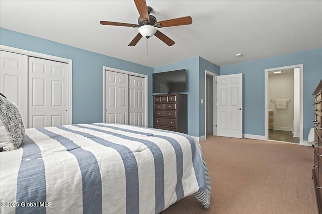 bedroom featuring ensuite bathroom, baseboards, a ceiling fan, multiple closets, and carpet flooring