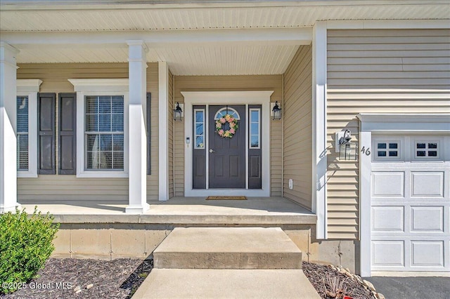 view of exterior entry with a garage and a porch