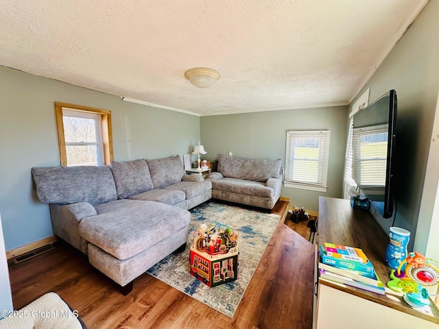 living area featuring visible vents, a textured ceiling, wood finished floors, and a wealth of natural light