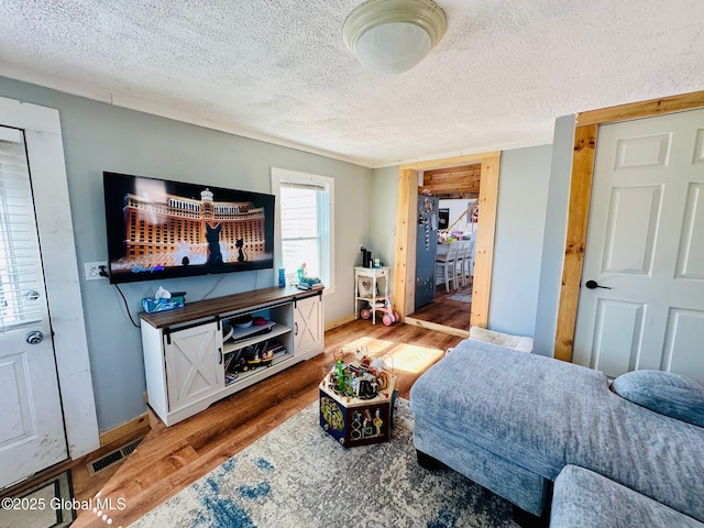 bedroom featuring visible vents, a textured ceiling, light wood finished floors, and baseboards